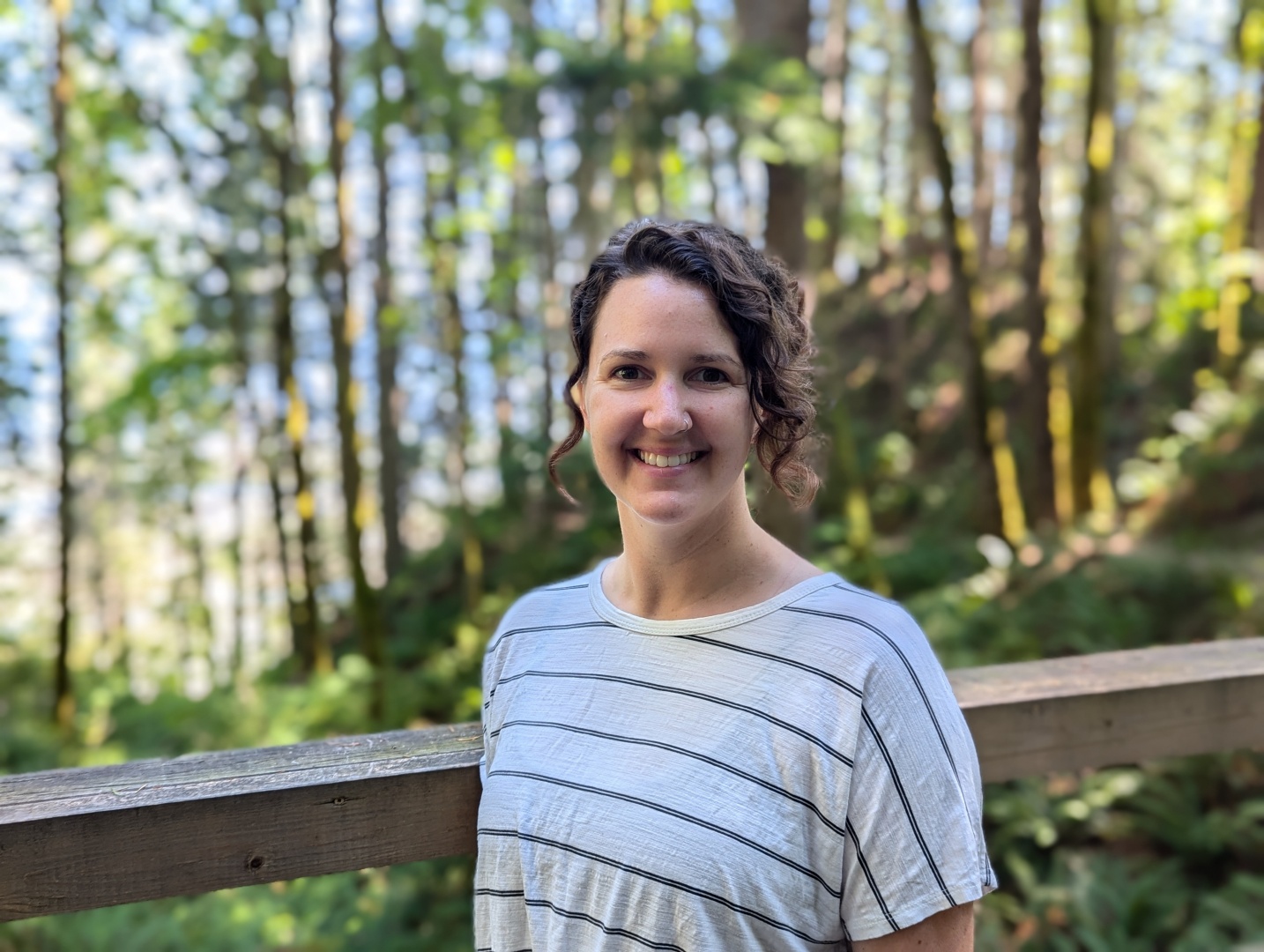 Kaitlyn smiling at the camera with a nature backdrop behind her.